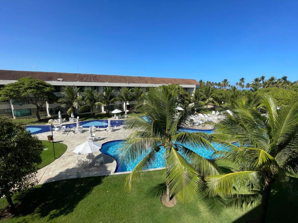 una vista sul mare di un resort con piscina e palme di Luxo à Beira-Mar - Flat 2 Quartos no Carneiros Beach Resort a Praia dos Carneiros