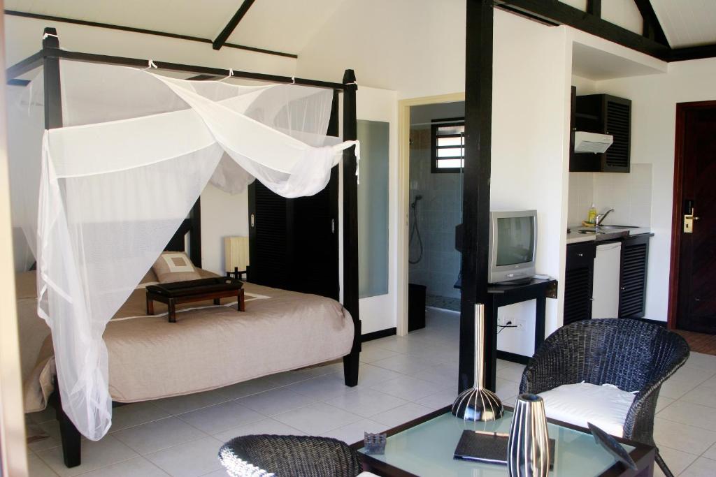 Païta的住宿－Rivland Resort，一间卧室配有一张带桌椅的天蓬床