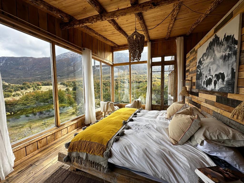 - une chambre avec un grand lit dans une pièce dotée de fenêtres dans l'établissement Alto Castillo, à Villa Cerro Castillo