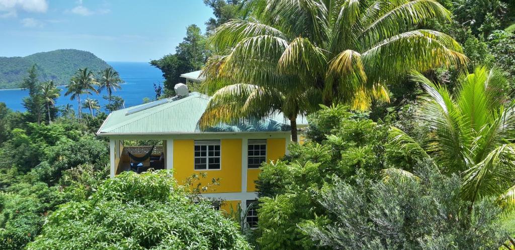 una casa amarilla en medio de árboles en Mango Garden Cottages en Tanetane