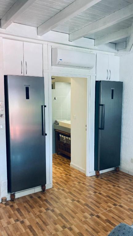 two black refrigerators in a room with a kitchen at Duplex à 50m de la plage du Diamant avec parking in Le Diamant