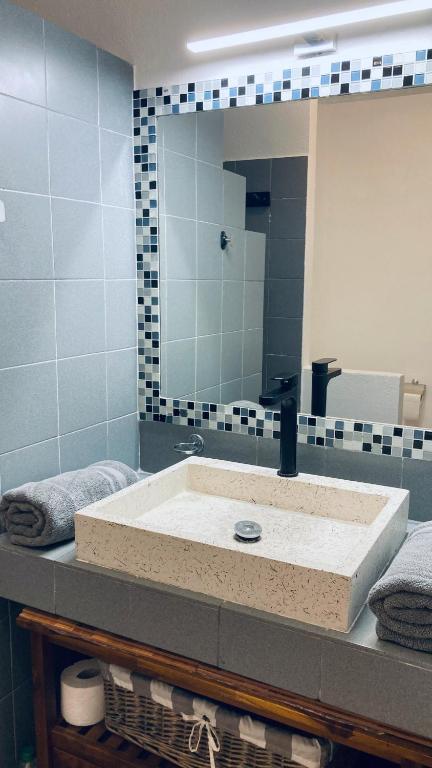 a bathroom with a sink with a large mirror at Duplex à 50m de la plage du Diamant avec parking in Le Diamant