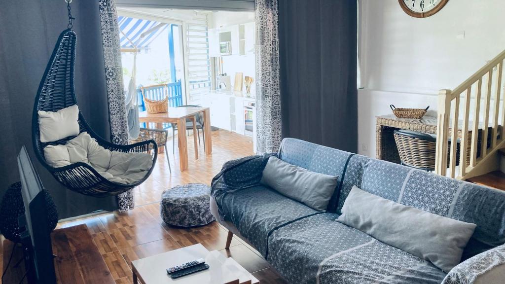 a living room with a blue couch and a swing at Duplex à 50m de la plage du Diamant avec parking in Le Diamant