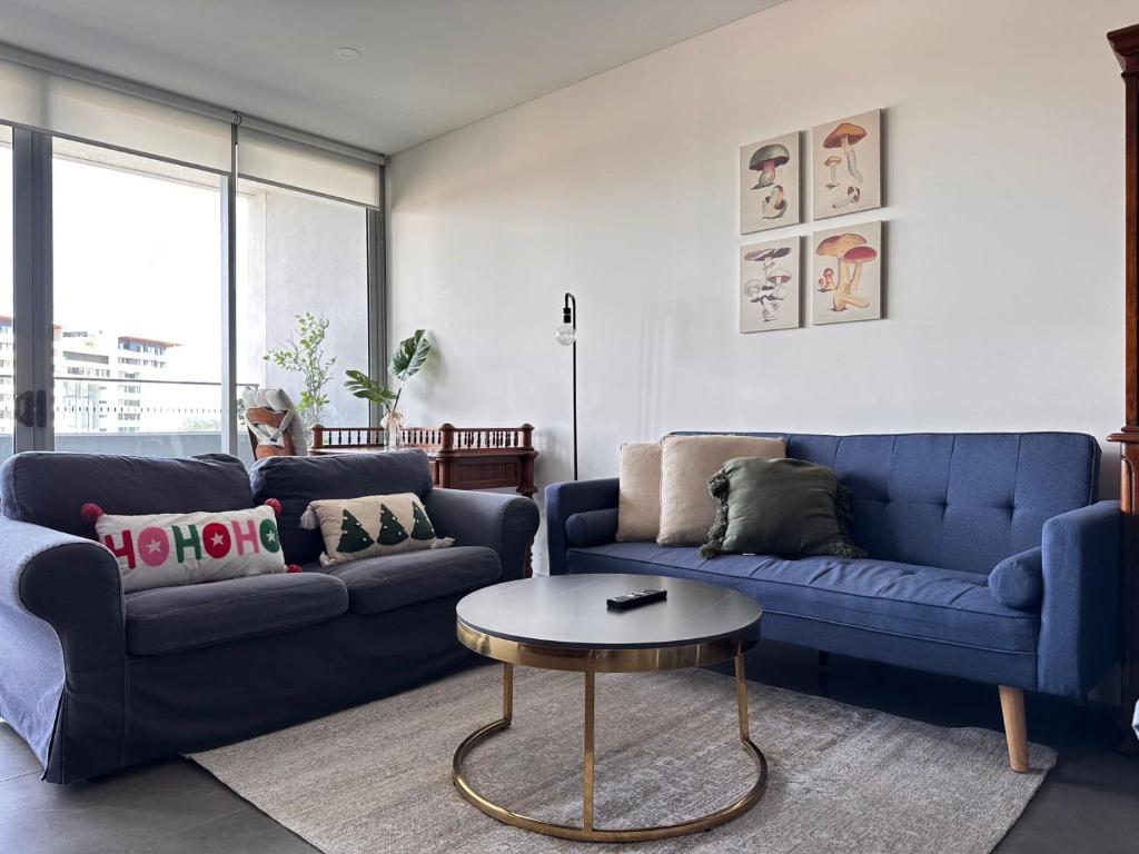 a living room with two blue couches and a table at Olympic park&Luxury 2b2b1p Apt pool& Free parking in Sydney