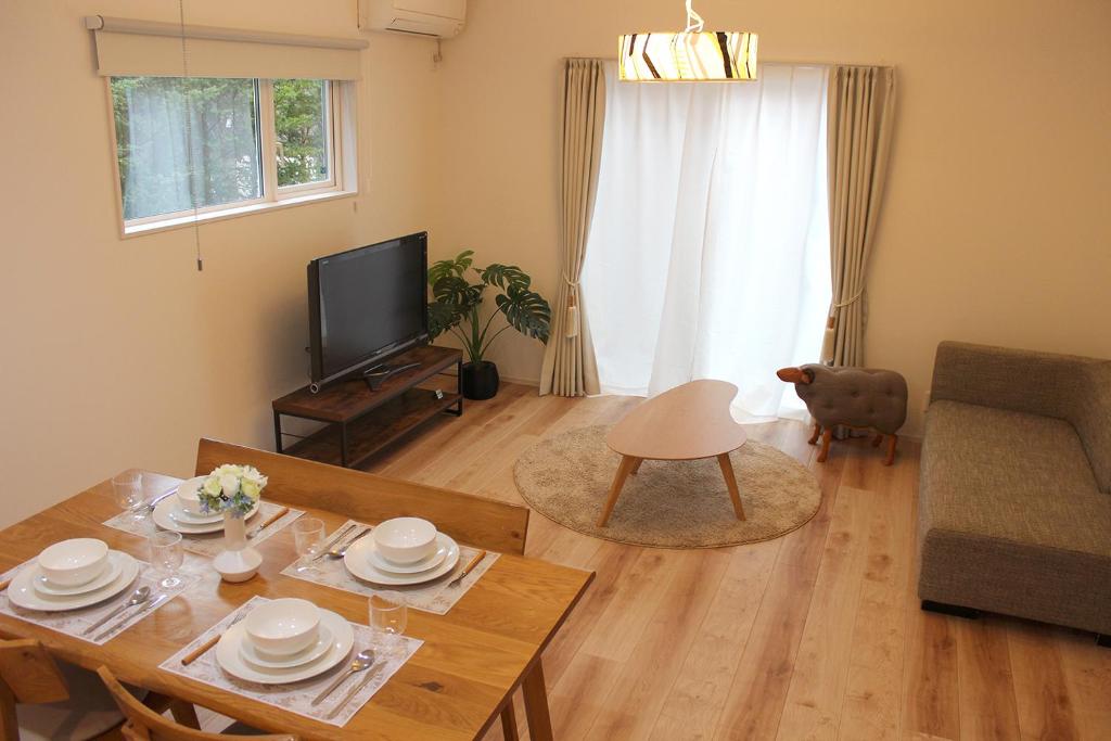ein Wohnzimmer mit einem Tisch und einem TV in der Unterkunft IZUMIYA2 in Shin-karuisawa