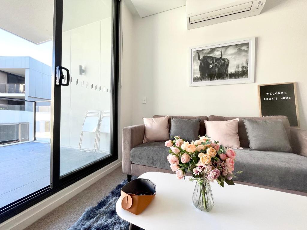 een woonkamer met een bank en een vaas met bloemen op een tafel bij Spacious cozy2BR close to OlympicPark free carpark in Sydney