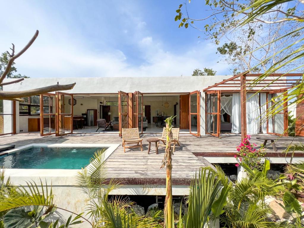 a house with a wooden deck and a swimming pool at Nowhere Villa Uluwatu in Uluwatu