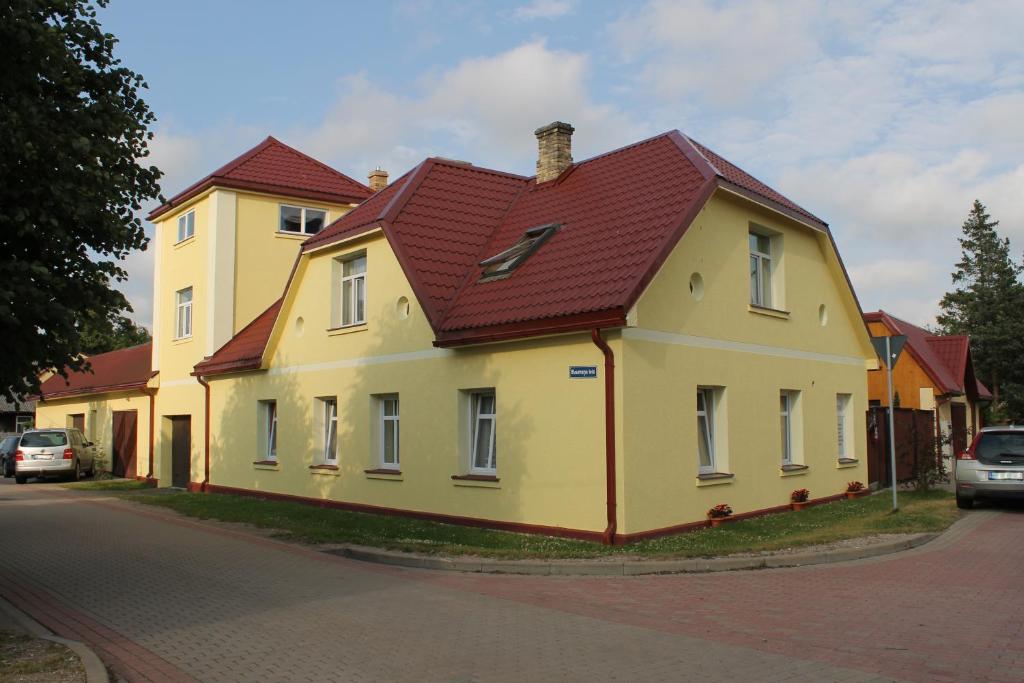 a yellow house with a red roof on a street at Amrai in Ventspils
