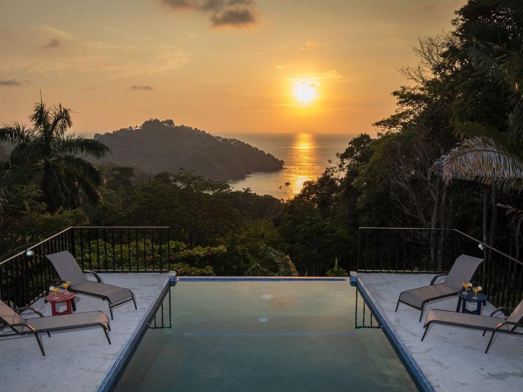 a pool with a view of the ocean at sunset at Alta Vista Villas Vacation Rentals in Manuel Antonio