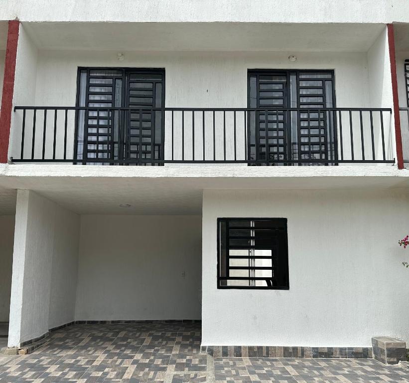 Edificio blanco con puertas negras y balcón en Alojamiento en Neiva en Santa Rosalía de Guagua
