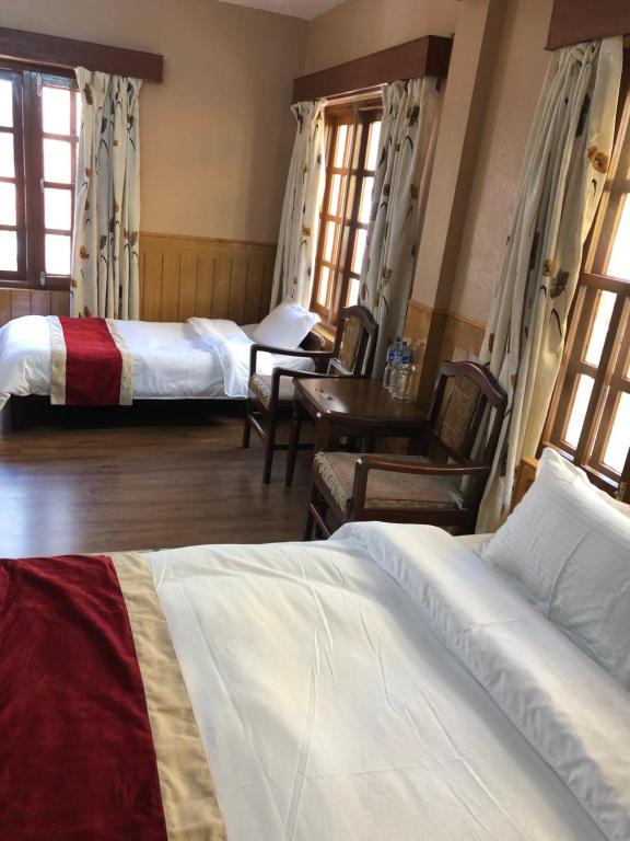 a bedroom with three beds and a table and chairs at Boudha Dungkar guest house in Kathmandu