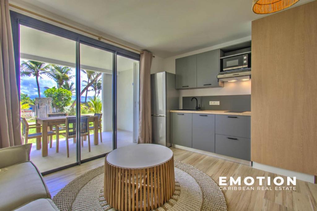 a kitchen with a table and a dining room with a balcony at Studio Alamanda Baie Orientale in Orient Bay