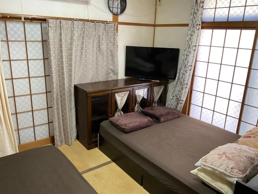 1 dormitorio con sofá, TV y ventanas en ゆーみー. en Meinohama