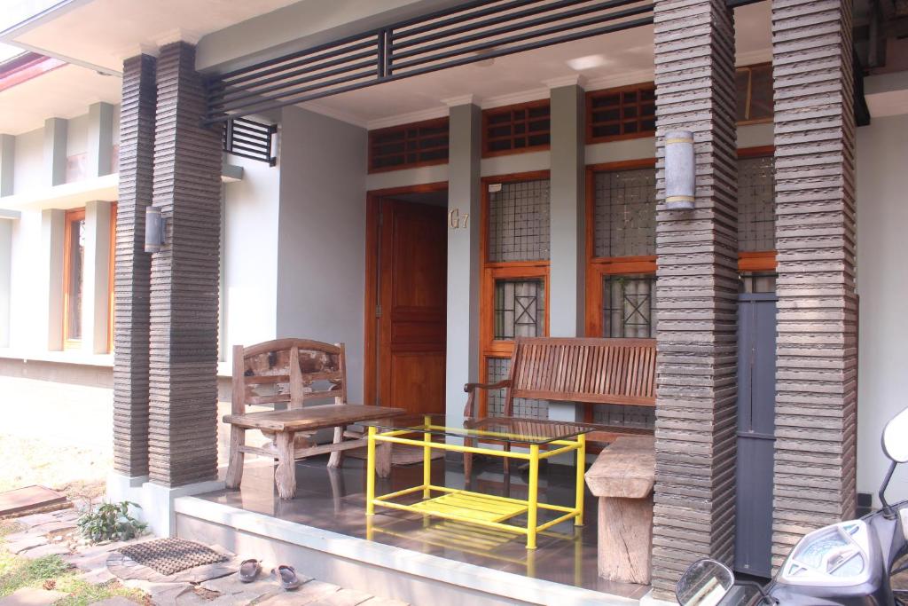 um alpendre de uma casa com um banco e uma mesa em Homestay Bougenville Antapani Syariah em Bandung