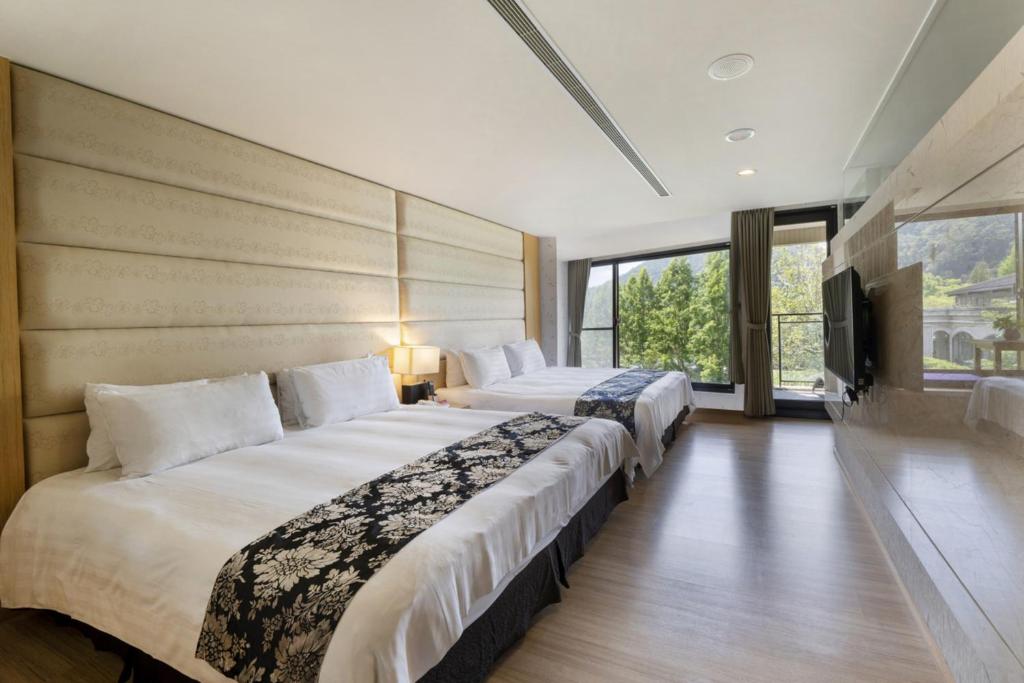 a hotel room with two beds and a flat screen tv at Tai-Yi Red Maple Resort in Puli