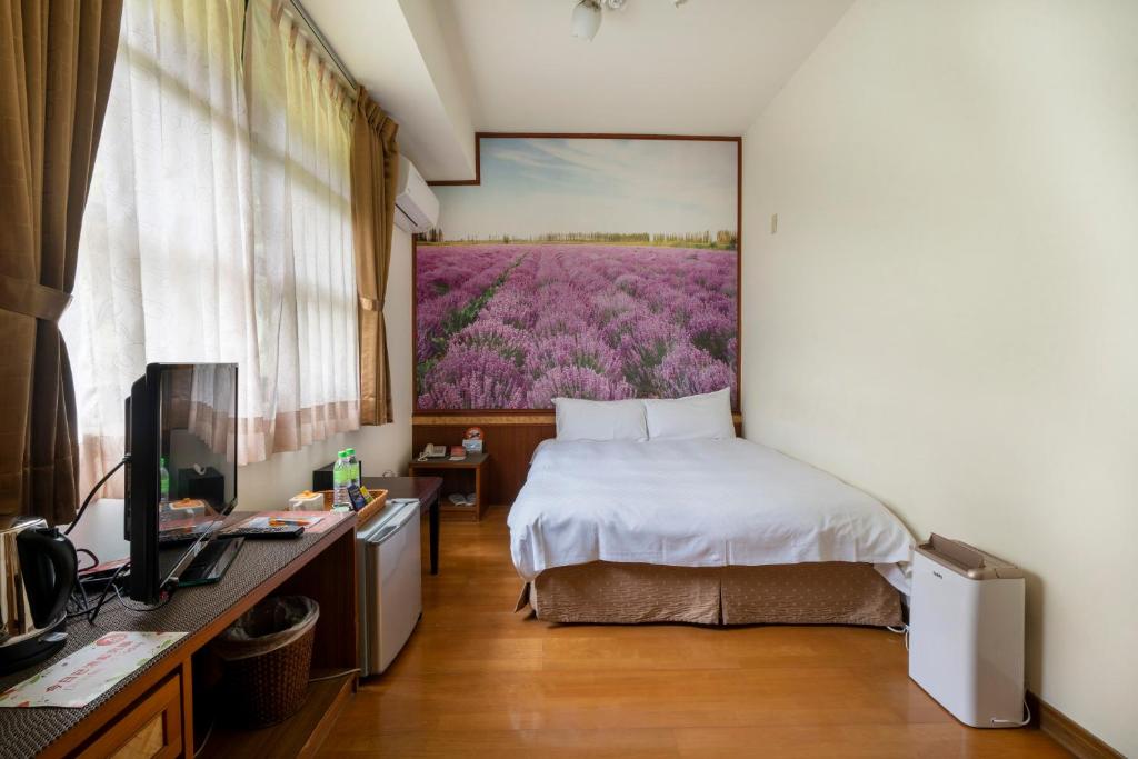 a bedroom with a bed and a painting on the wall at Tai-Yi Red Maple Resort in Puli