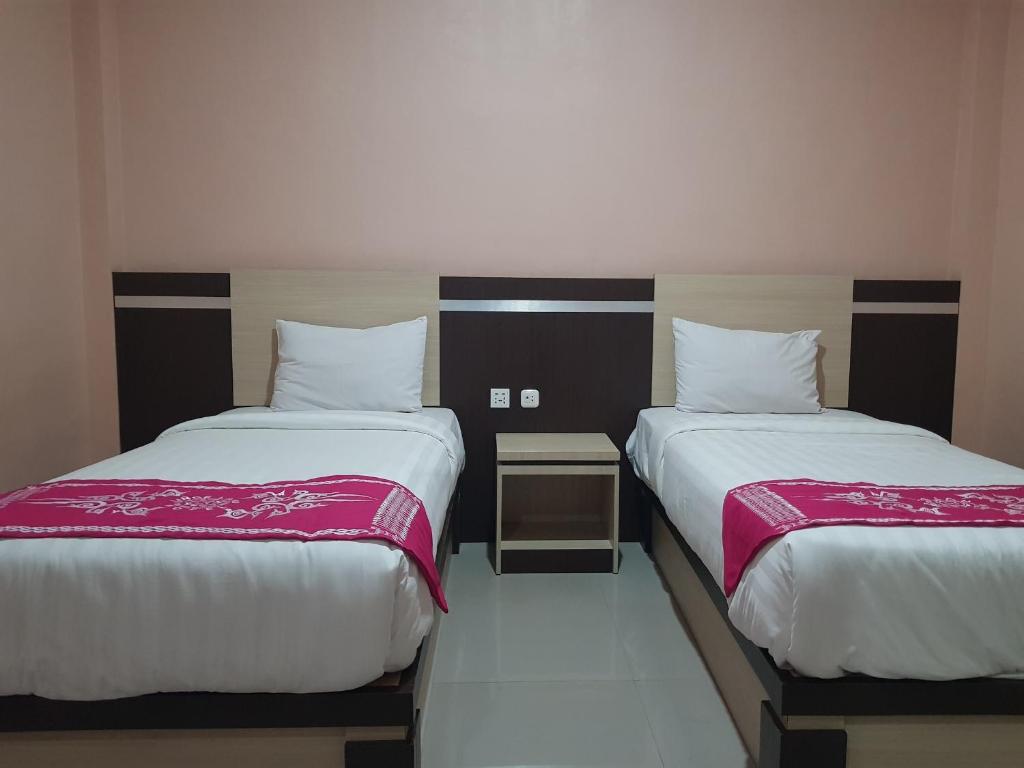 dos camas sentadas una al lado de la otra en una habitación en Capital O 93263 Linge Land Hotel, en Takengon