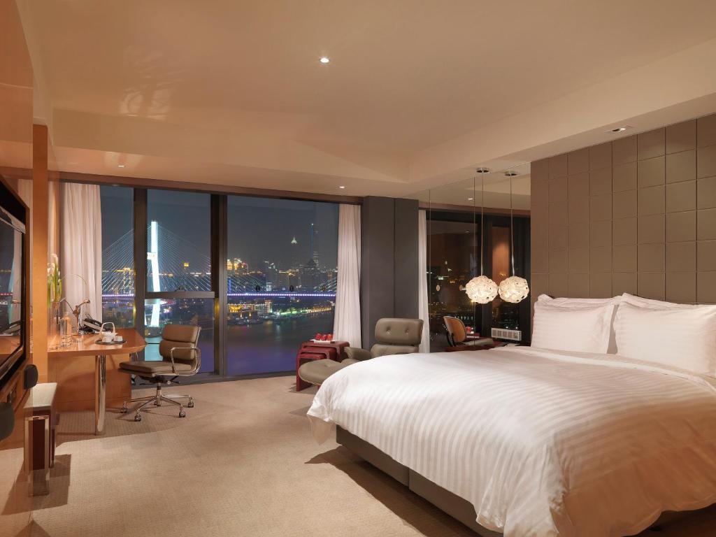 - une chambre avec un grand lit, un bureau et des chaises dans l'établissement InterContinental Shanghai Expo, an IHG Hotel, à Shanghai