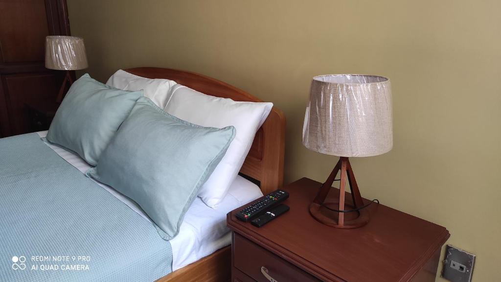 1 dormitorio con 1 cama con lámpara y mando a distancia en Departamento Frente a la Plaza Sucre de Tarija, wifi, ascensor, garaje extra, en Tarija