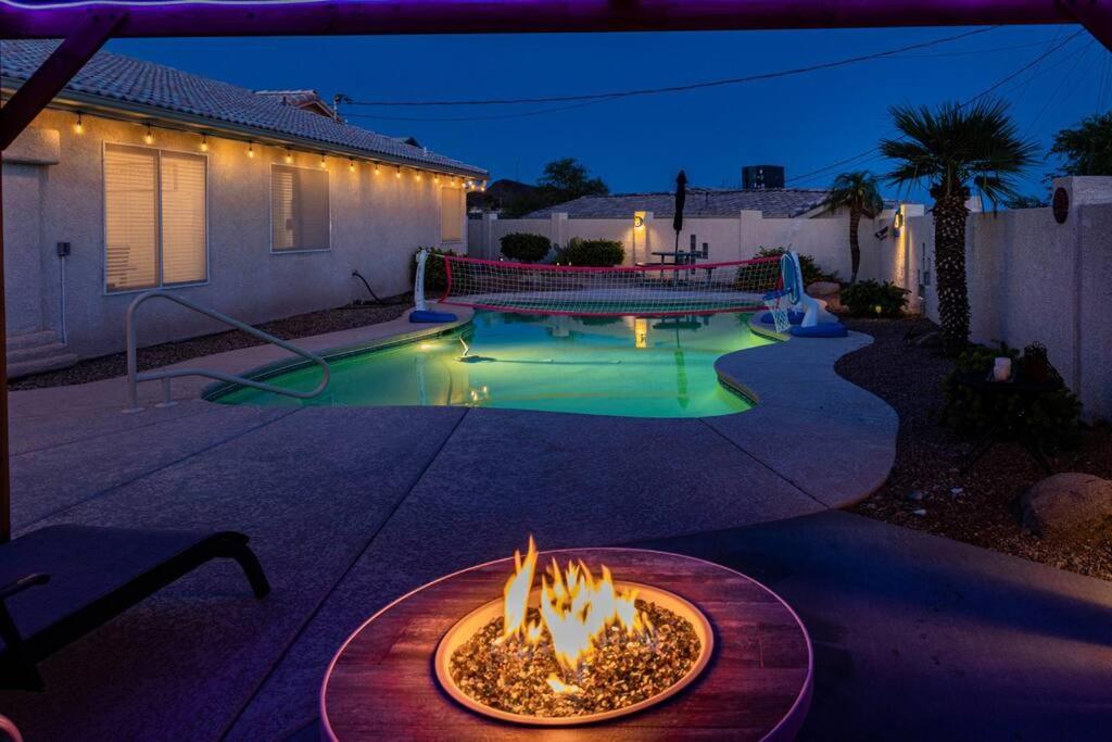un patio trasero con una hoguera y una piscina por la noche en Sunset Paradise . Pool . BBQ . Smart TV . Sleeps10, en Lake Havasu City