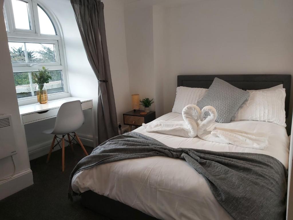 een slaapkamer met een bed met witte lakens en een raam bij The Cozy Landport Loft in Portsmouth