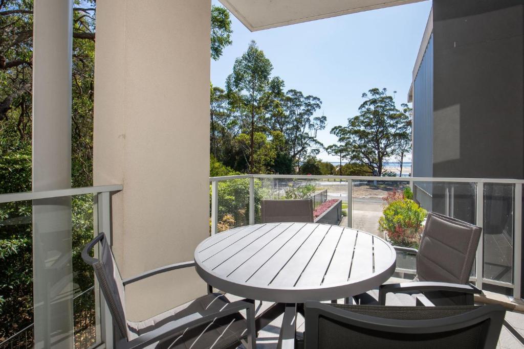 a patio with a table and chairs on a balcony at Bay Blu - Pet Friendly - Waterfront in Huskisson