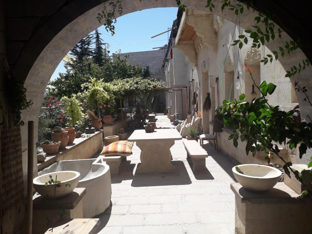 un arco in un vicolo con tavolo e piante in vaso di Mozaik Stone Hotel ad Avanos