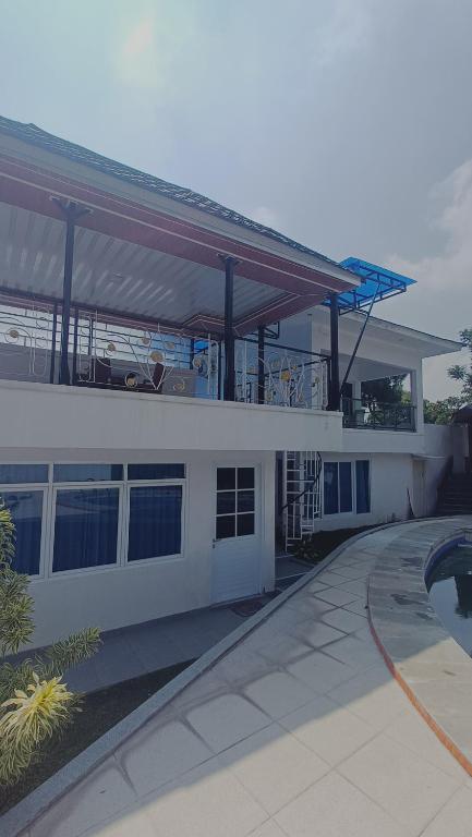 a large white building with a balcony and a pool at Villa Dalia Puncak P2-12 in Cianjur