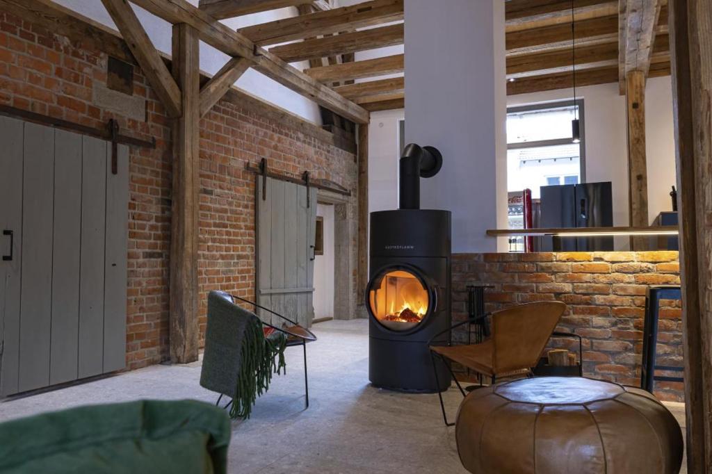 a living room with a brick wall and a fireplace at Landurlaub mit neugierigen Blicken in den Pferdestall, eingezäuntem Garten, Kamin und Sauna in Rot am See