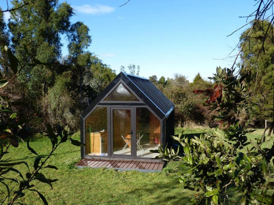 ein kleines Haus mit einem Fenster im Gras in der Unterkunft Tiny House Camino a Cascadas, Lago Llanquihue in Puerto Octay