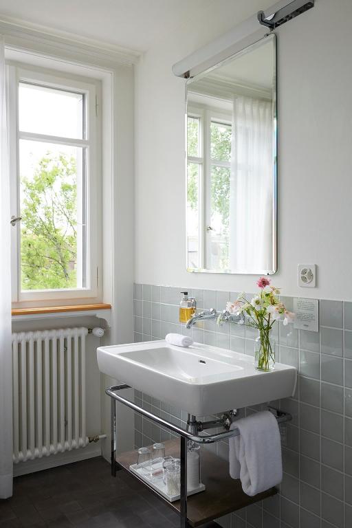 bagno bianco con lavandino e specchio di Signau House & Garden Boutique Hotel Zürich a Zurigo