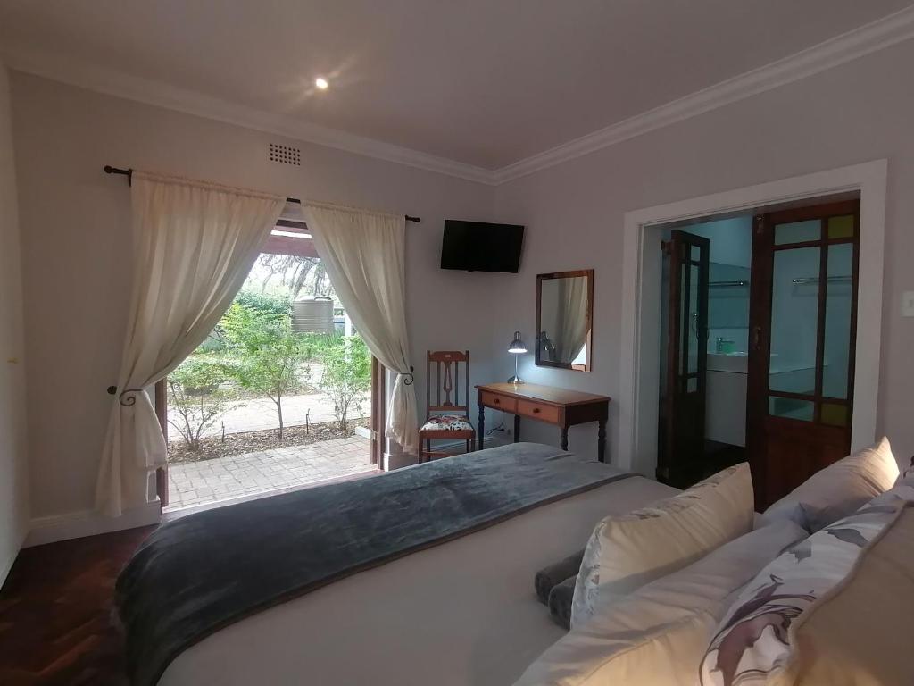 a bedroom with a bed and a desk and a window at Beulah Lodge in Cape Town
