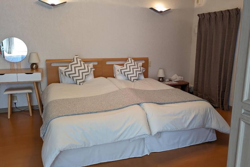 una camera con un grande letto, una scrivania e uno specchio di Roomy 4BR Home Sleeps 9／ShinOsaka／Large Groups ad Osaka