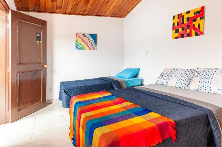 1 dormitorio con 2 camas y una manta colorida en Hotel Habitat Hospedaje, en Bogotá