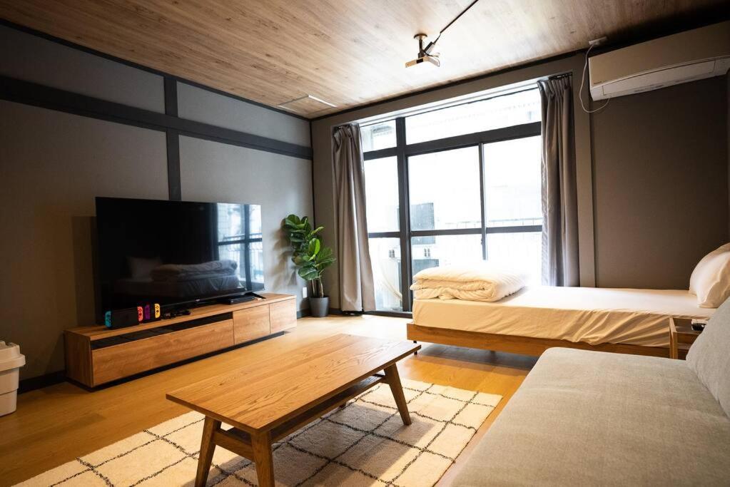 een kamer met een bed en een televisie en een tafel bij TasoneUrbanStayOsaka なんば日本橋黒門テナント2F in Osaka