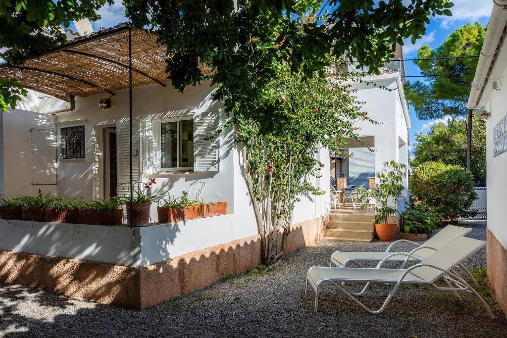 Uma casa branca com um banco à frente. em Es Claper em Cala Ratjada