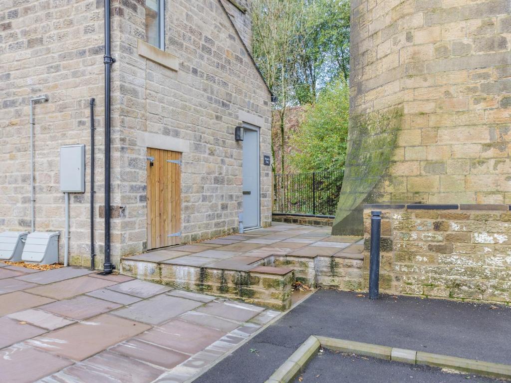 a brick building with a door and a sidewalk at Weavers Snug in Haworth