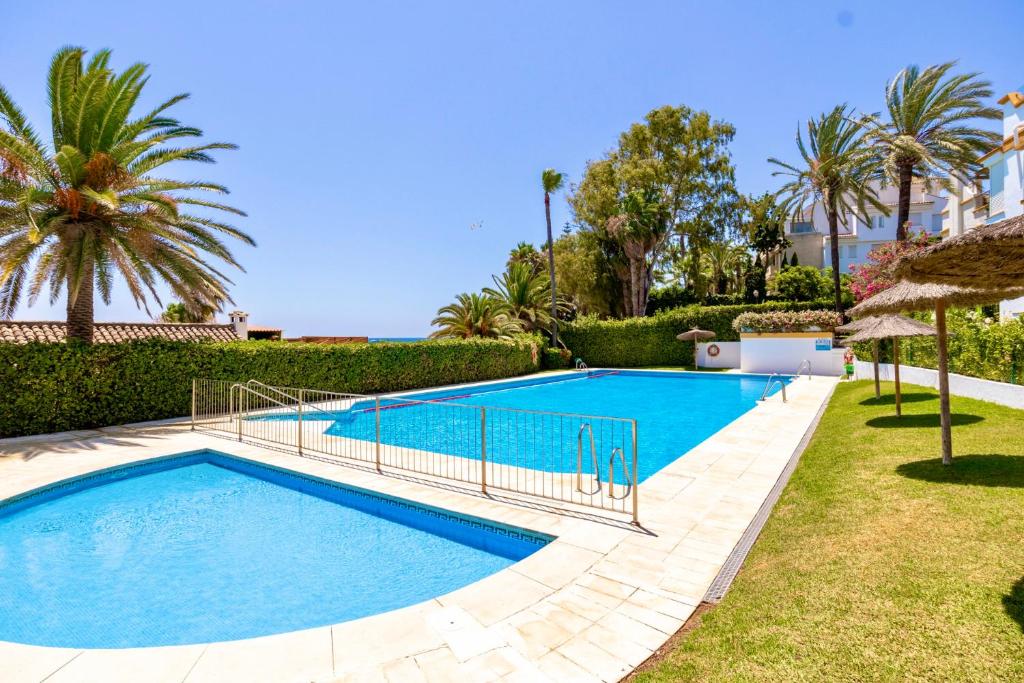 una piscina in una villa con palme di Marbella Trocadero Beach & Pool a Marbella