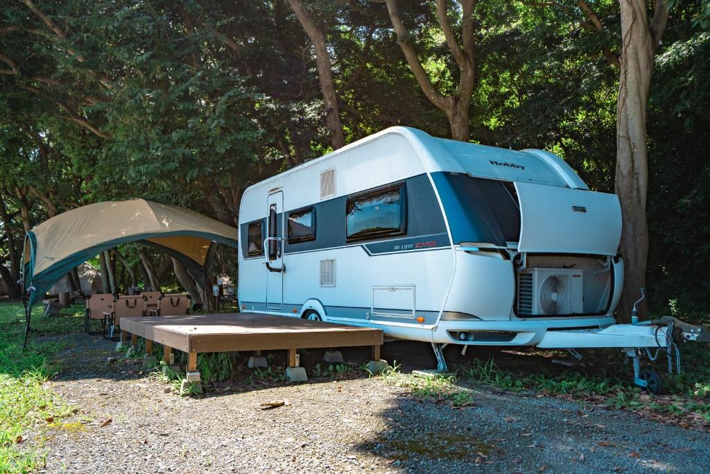 Una autocaravana azul y blanca estacionada junto a una tienda de campaña. en 長崎鼻ビーチリゾート, en Kakaji
