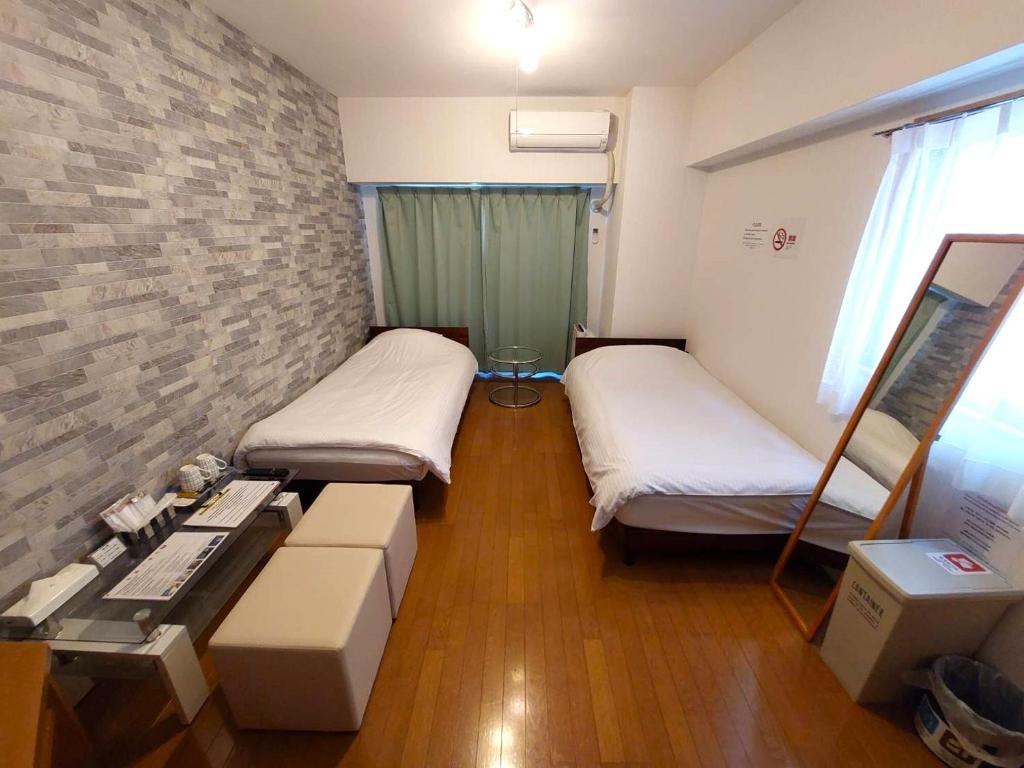 福岡市にあるComfort CUBE PHOENIX S KITATENJINのベッド2台とテーブルが備わる小さな客室です。