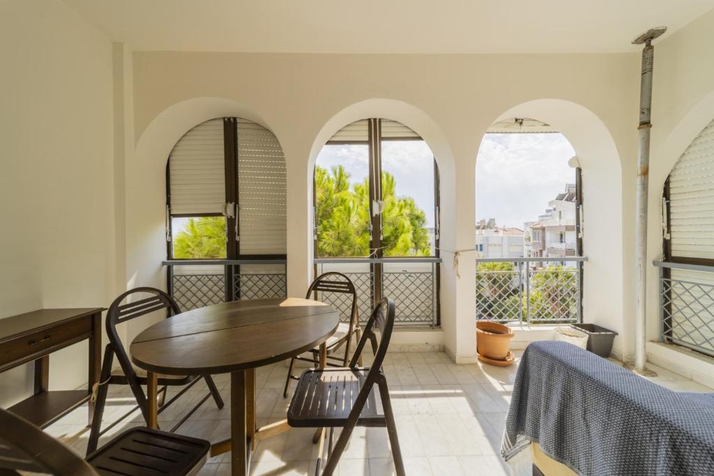 a dining room with a table and chairs and windows at Flat with Balcony 3 min to Fosforlu Beach in Antalya