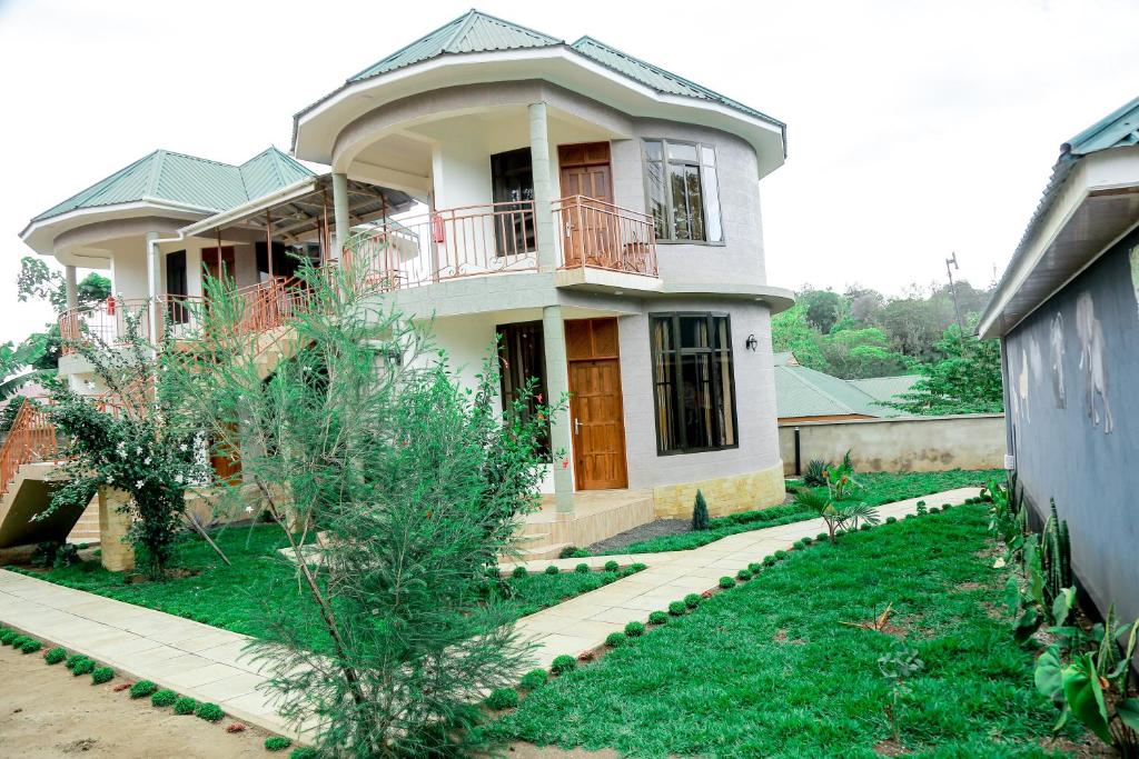 een huis met een balkon en een tuin bij Wademac Arusha Inn Hotel in Arusha