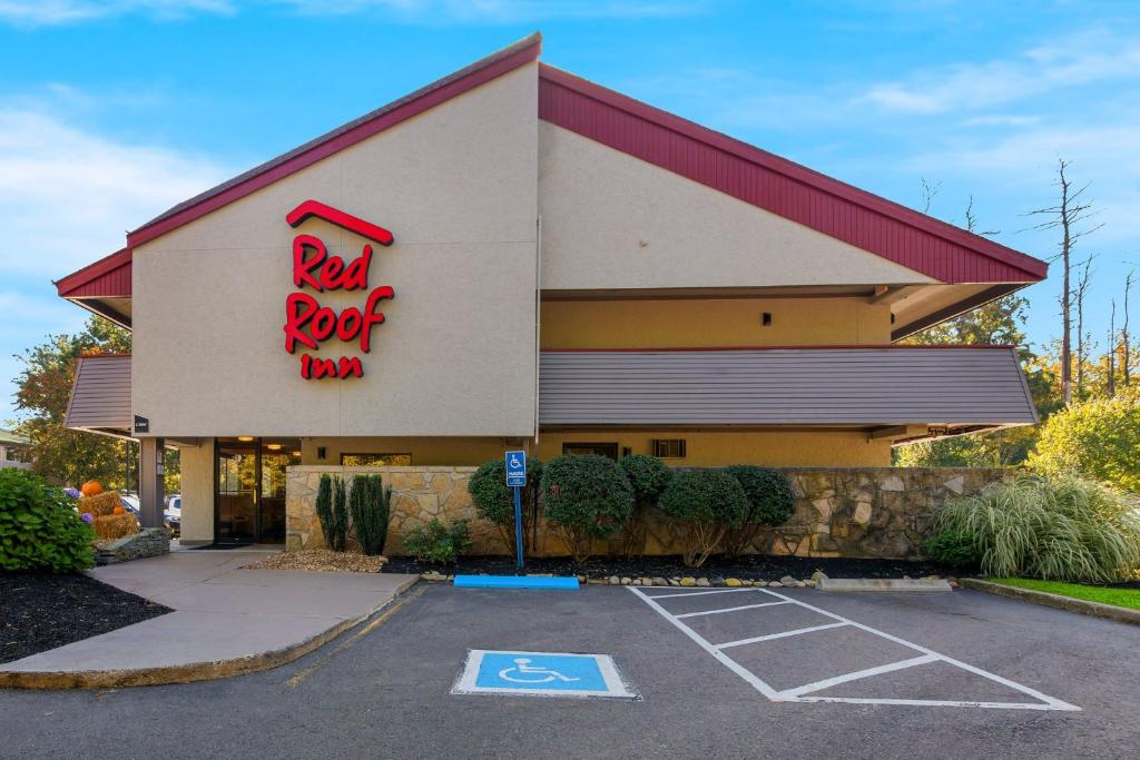 ein Gebäude mit einem Schild eines roten Gasthofs auf einem Parkplatz in der Unterkunft Red Roof Inn Salem in Salem