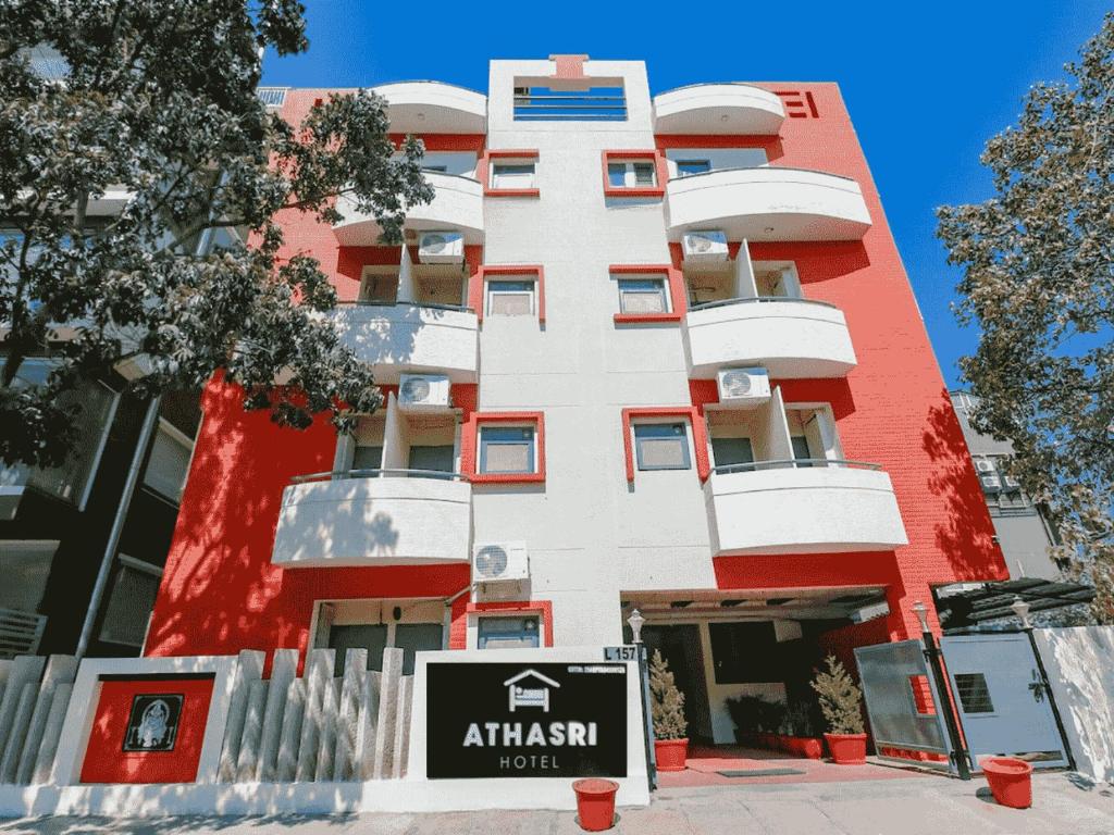 um edifício vermelho e branco com um sinal em frente em Athasri Hotel HSR Layout em Bangalore