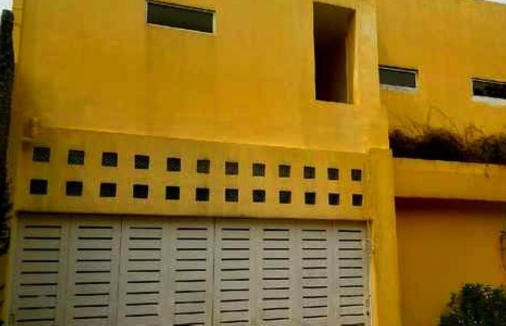 un bâtiment jaune avec une porte de garage blanche dans l'établissement OYO 93286 Yellow House Syariah, à Bogor