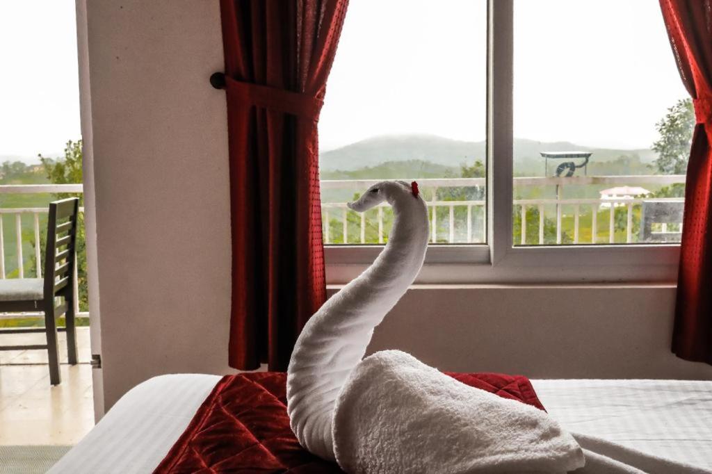 瓦戈曼的住宿－towersky hill resort CONCERN OF PINKY HOLIDAYS，一只白鸟站在床上,眺望着窗外