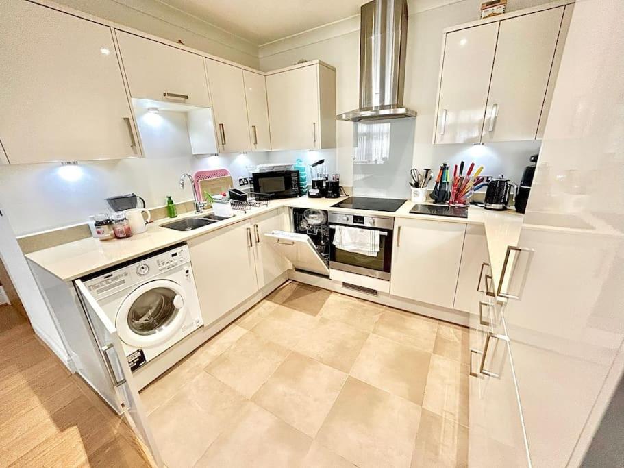 a kitchen with white cabinets and a washer and dryer at Lovely cosy apartment Bromley in Bickley