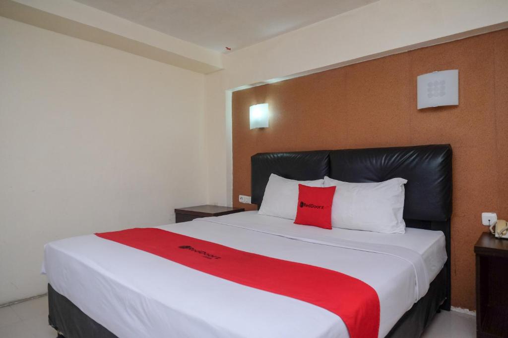 RedDoorz Plus At Grand Populer Hotel في ماكاسار: غرفة نوم مع سرير كبير مع وسادتين حمراء
