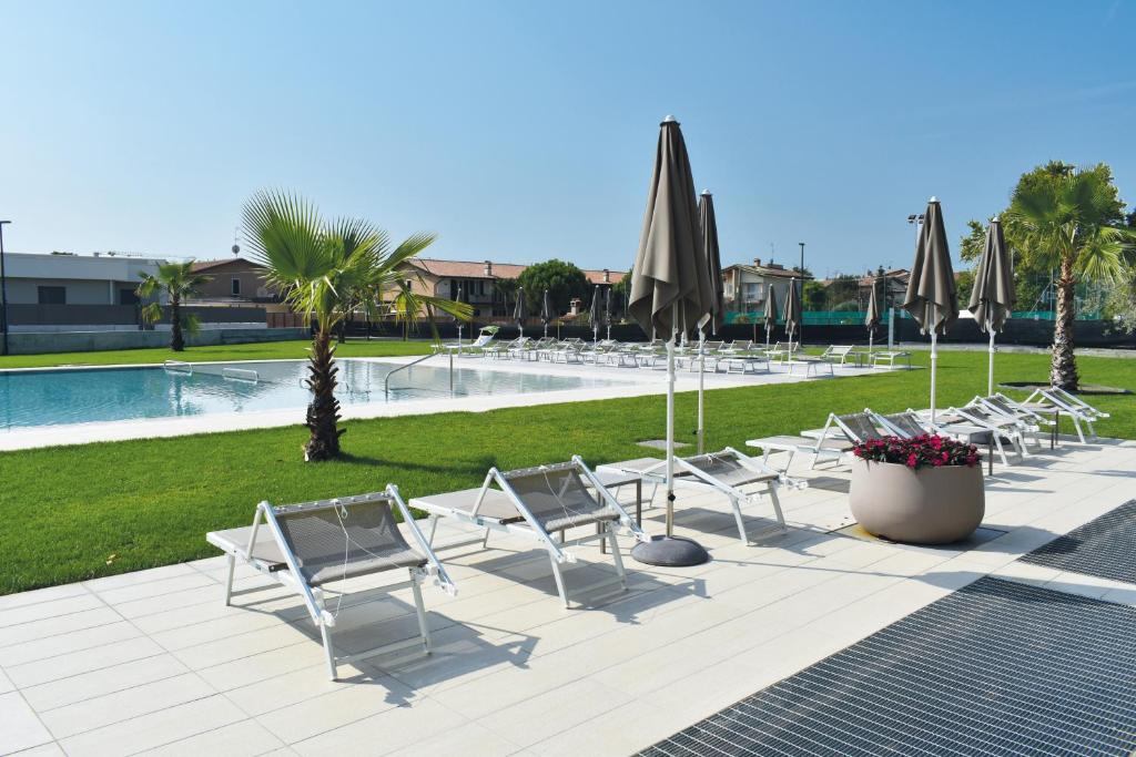 a row of chairs and umbrellas next to a pool at Residence La Magnolia - Aparments in Lazise
