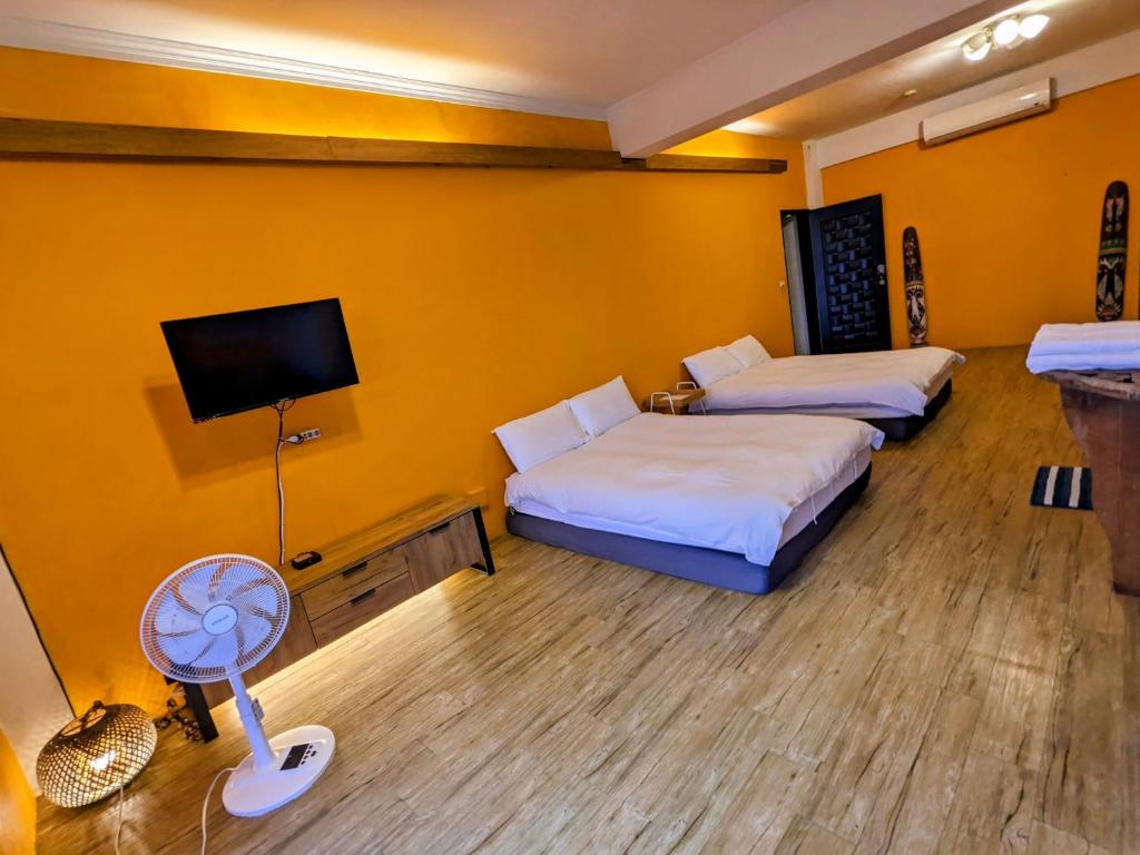 a room with two beds and a tv and a fan at Blackport Seaview Homestay in Yanliau